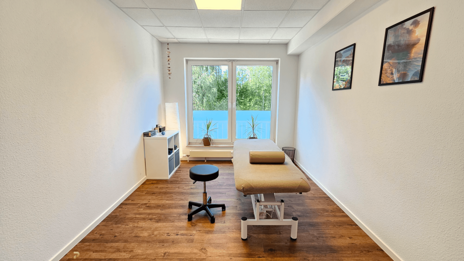 Behandlungsraum Helle Therapieräume mit einer Liege und Blick auf einen Garten.