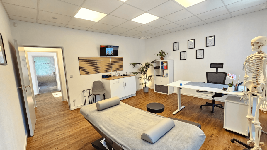 Diagnostik & Beratungsraum Behandlungsraum mit Behandlungsliege, Schreibtisch und anatomischem Modell.